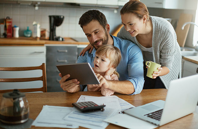 Young family using tablet with documents on desk